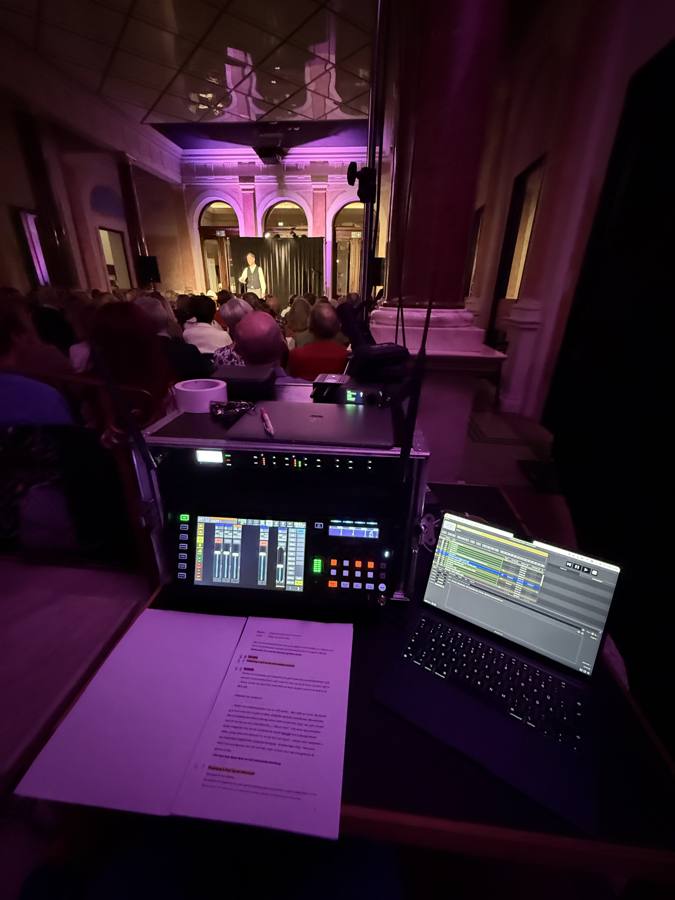 Lichtkonsole und Laptop mit QLab/Light-Cues, im Hintergrund Bühne mit Performer