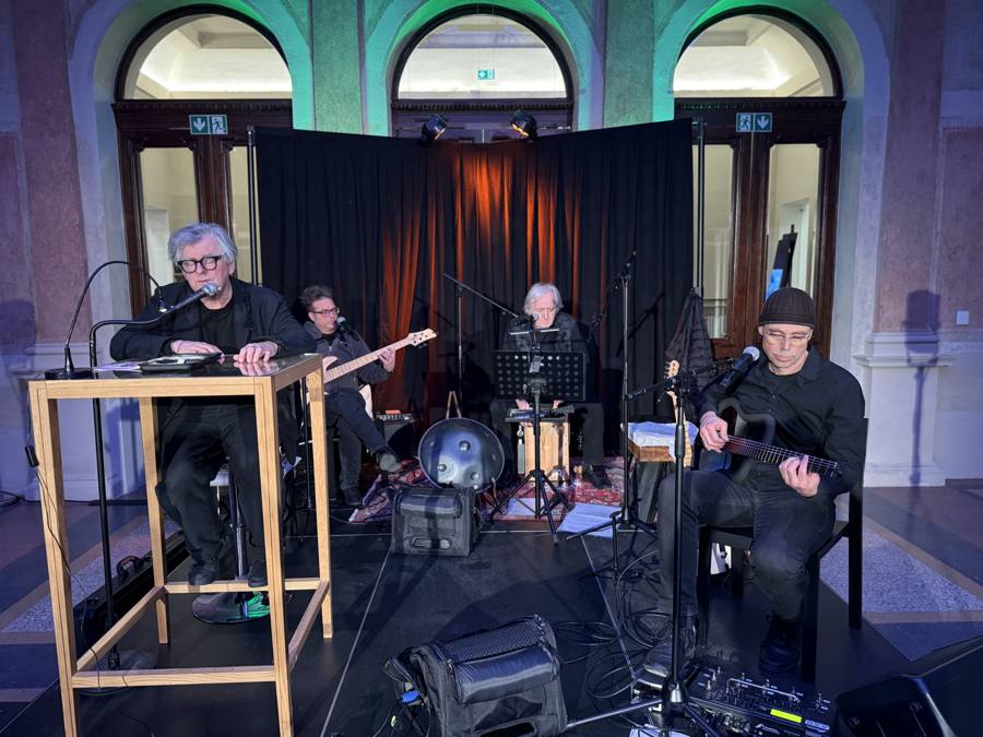 Lesung mit Musikbegleitung — Stehpult, Kontrabass, Gitarre vor schwarzem Hintergrund