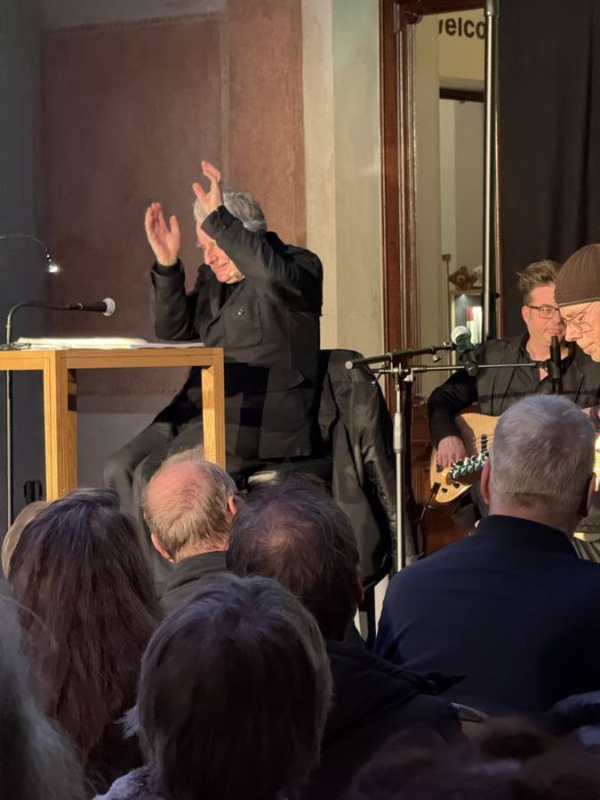 Performer in Bewegung mit Gitarre, Publikum nah am Geschehen
